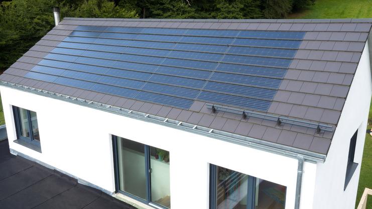 Dachansicht eines modernen Hauses mit Solarpanelen auf einem schrägen Dach und weißen Wänden.