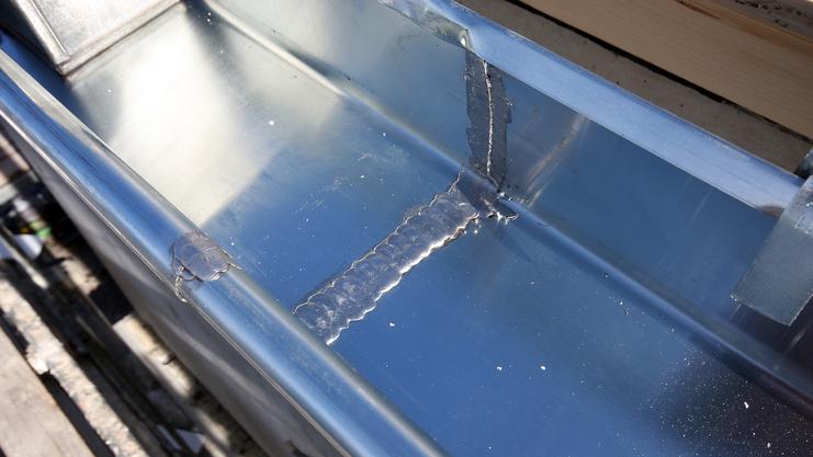 Nahaufnahme einer glänzenden Metalloberfläche mit Schweißnaht und vernetzenden Kanten auf einer Konstruktion.